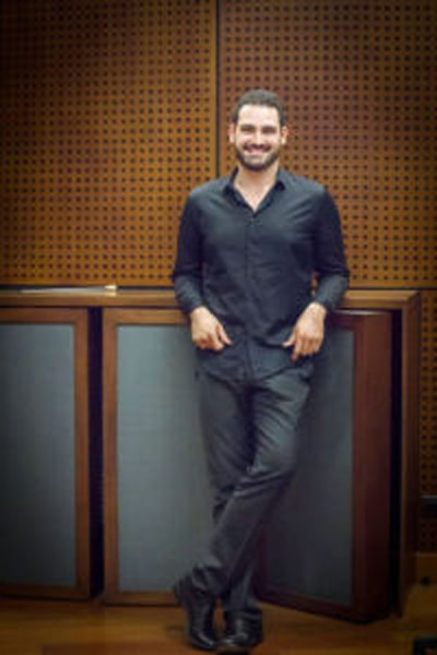 Juan David Osorio, smiling and leaning on a large speaker cabinet